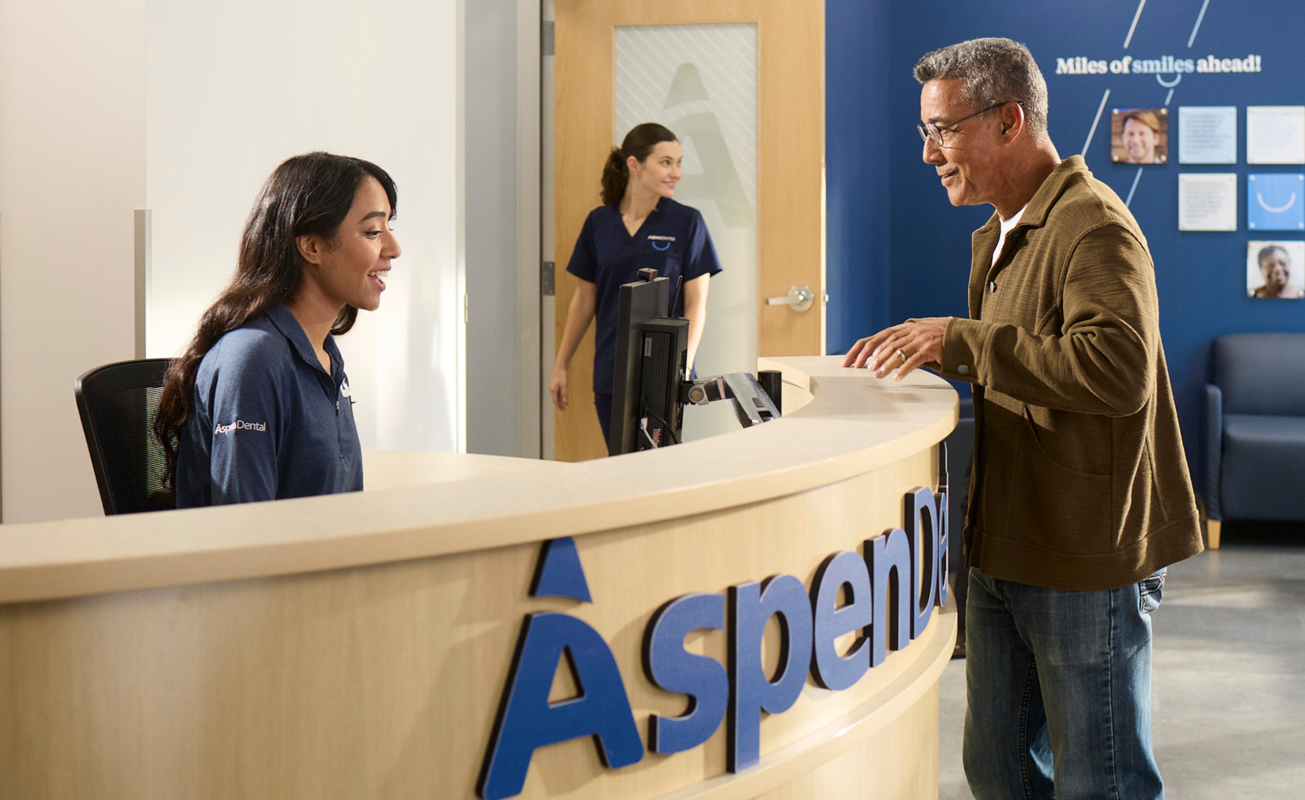 Male patient checking in at the reception desk inside an Aspen Dental office.