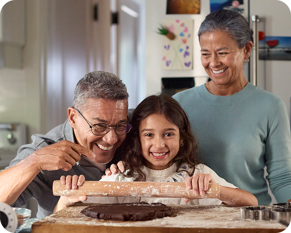 Grandparents and granddaughter happily rolling out dough together
