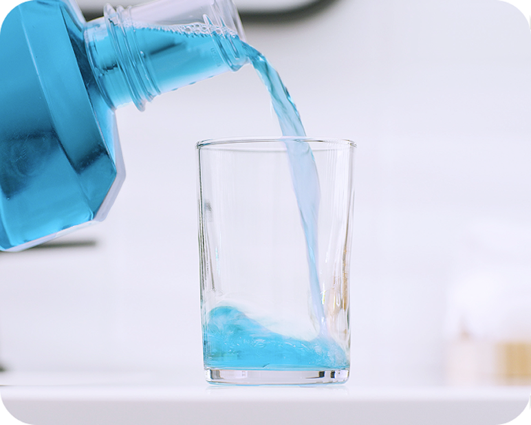 Alt text:
Blue mouthwash being poured into a glass for oral care.