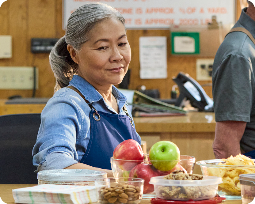 Alt text:
Woman preparing food at a counter with apples and containers.