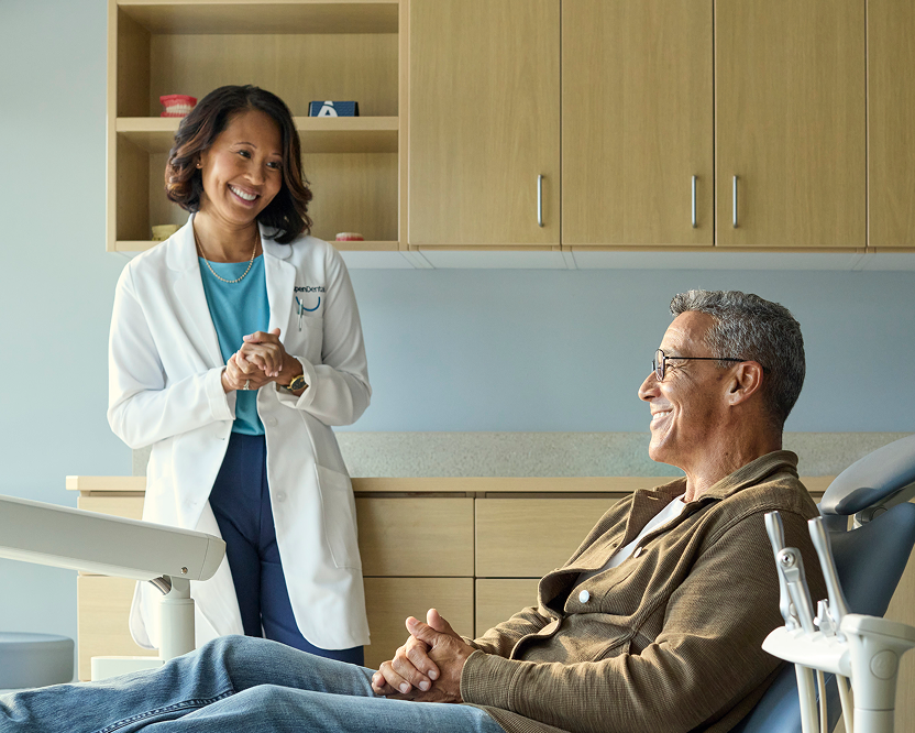 Alt text:
Aspen Dental professional speaking with an older adult man seated comfortably in a dental chair.