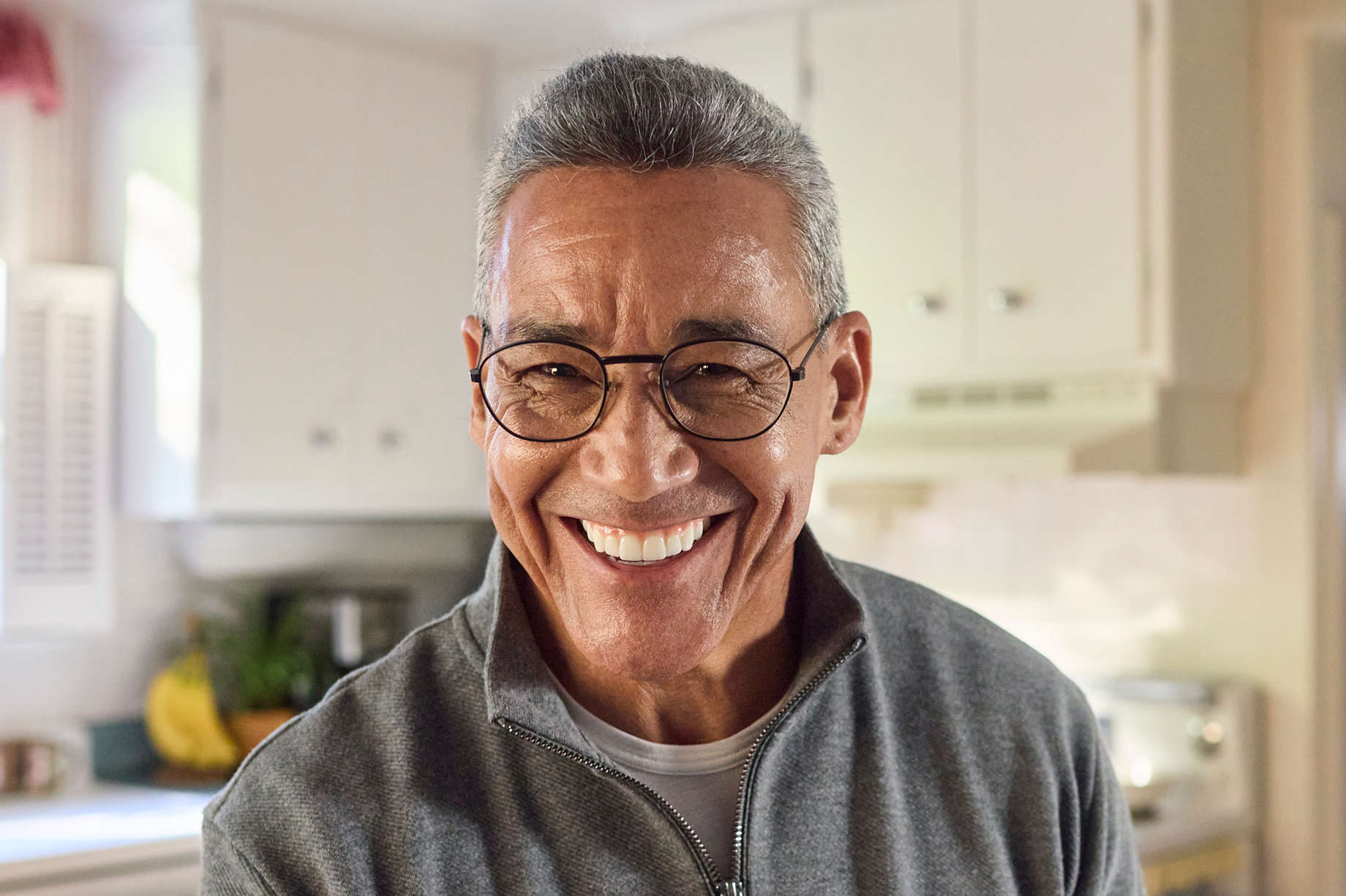 Smiling older adult man indoors with a bright, confident smile, representing confidence related to dental care.