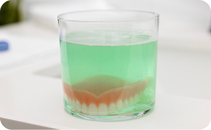 Denture soaking in a glass of cleaning solution.