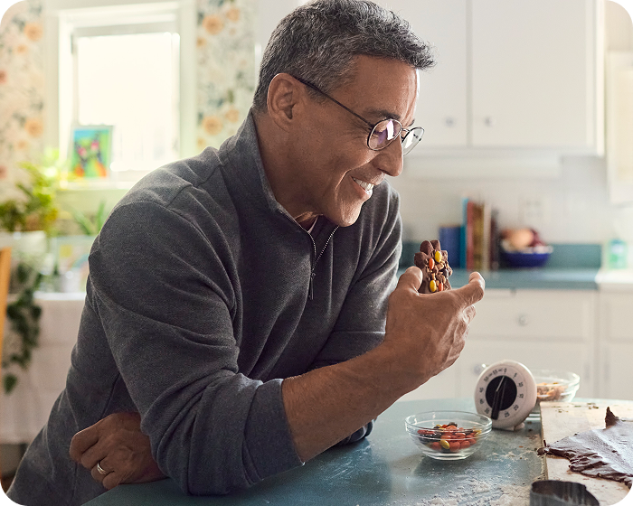 Man smiling while eating in his kitchen, demonstrating the ability to bite and chew comfortably with dental implants.