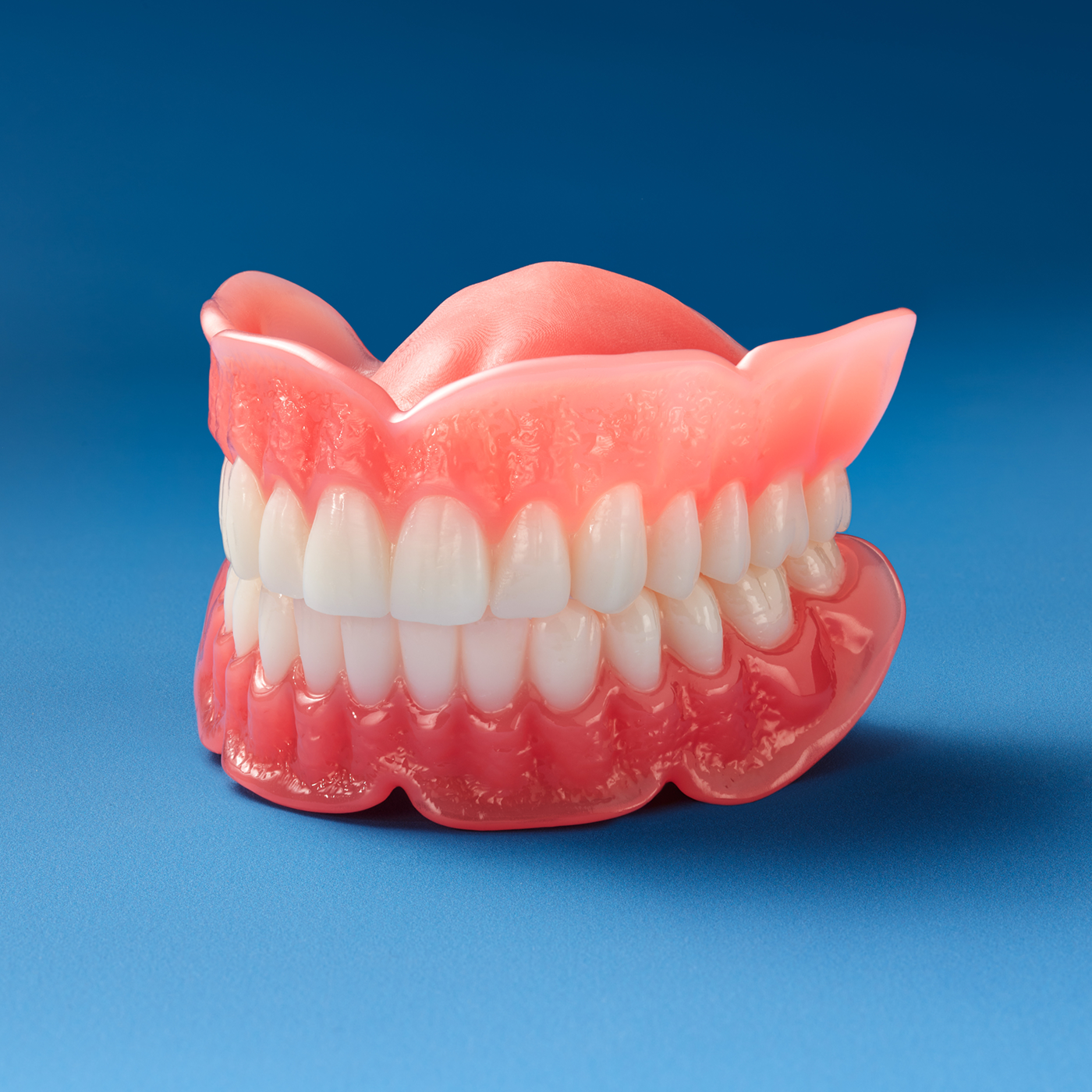 Full denture model showing upper and lower artificial teeth with pink gum base.