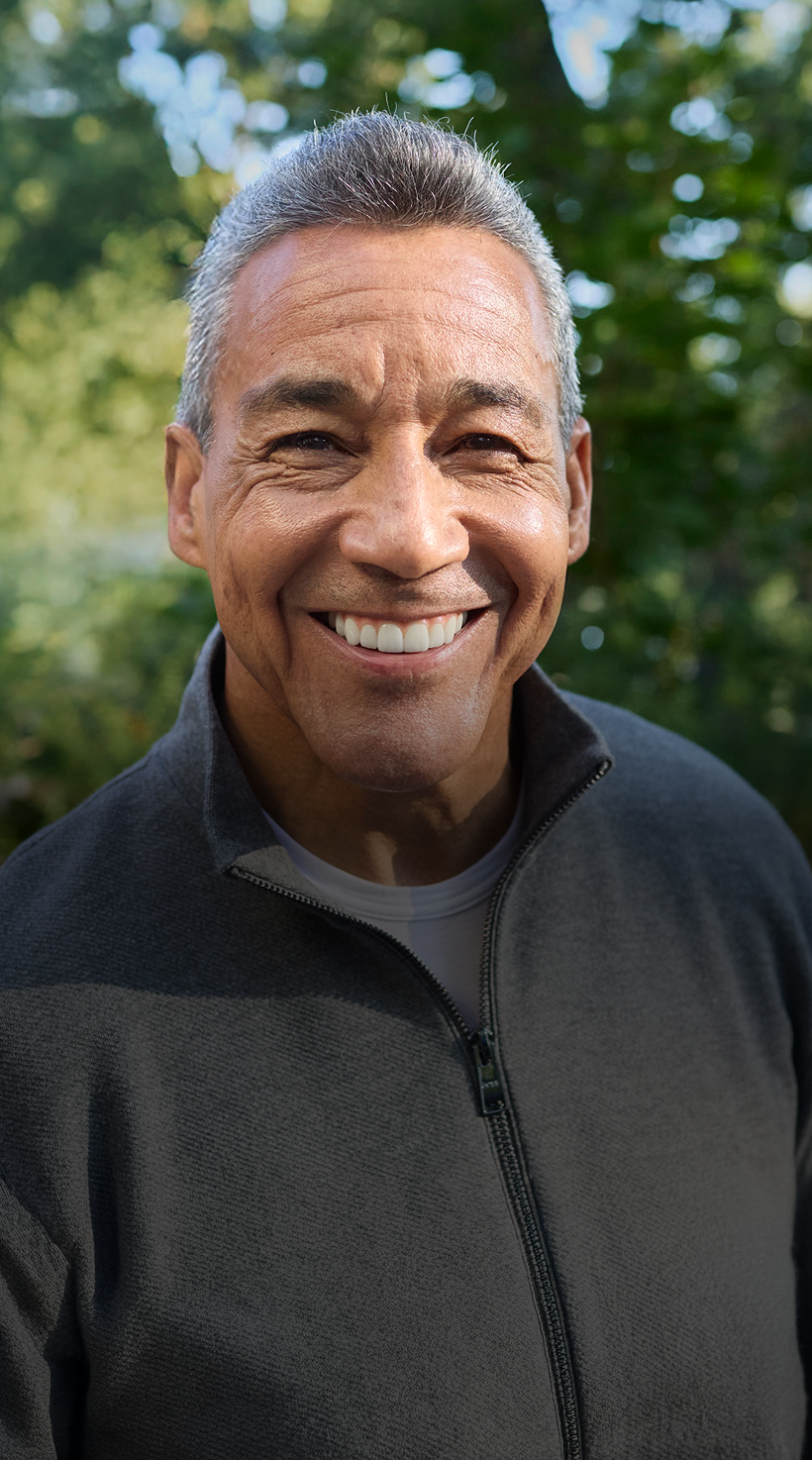 A smiling man with gray hair in a dark jacket, outdoors