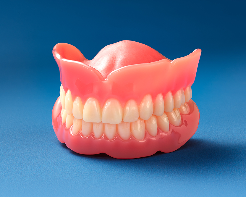 A set of artificial upper and lower classic dentures with a pink gum-like base and white teeth model shown as an option to replace missing teeth.