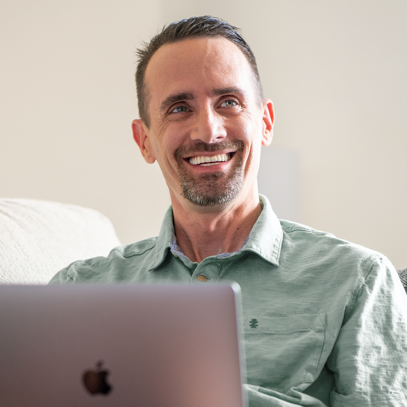 Smiling man reviewing flexible payment plans and financing options for dental implants on his laptop