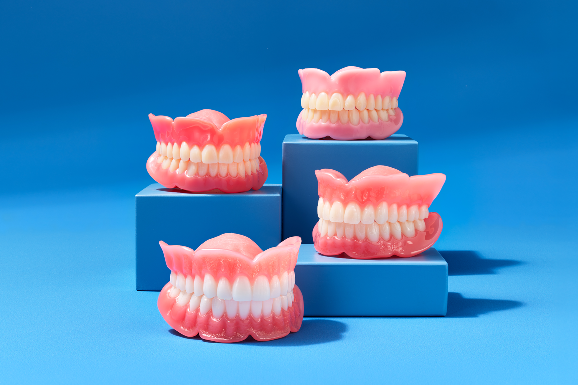 Displaying full denture prosthetic models showing different tooth replacement options behind a blue background.