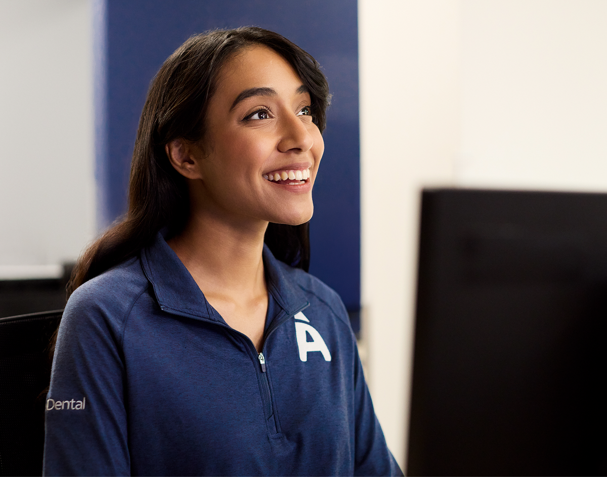 A smiling woman in a blue shirt looks engaged