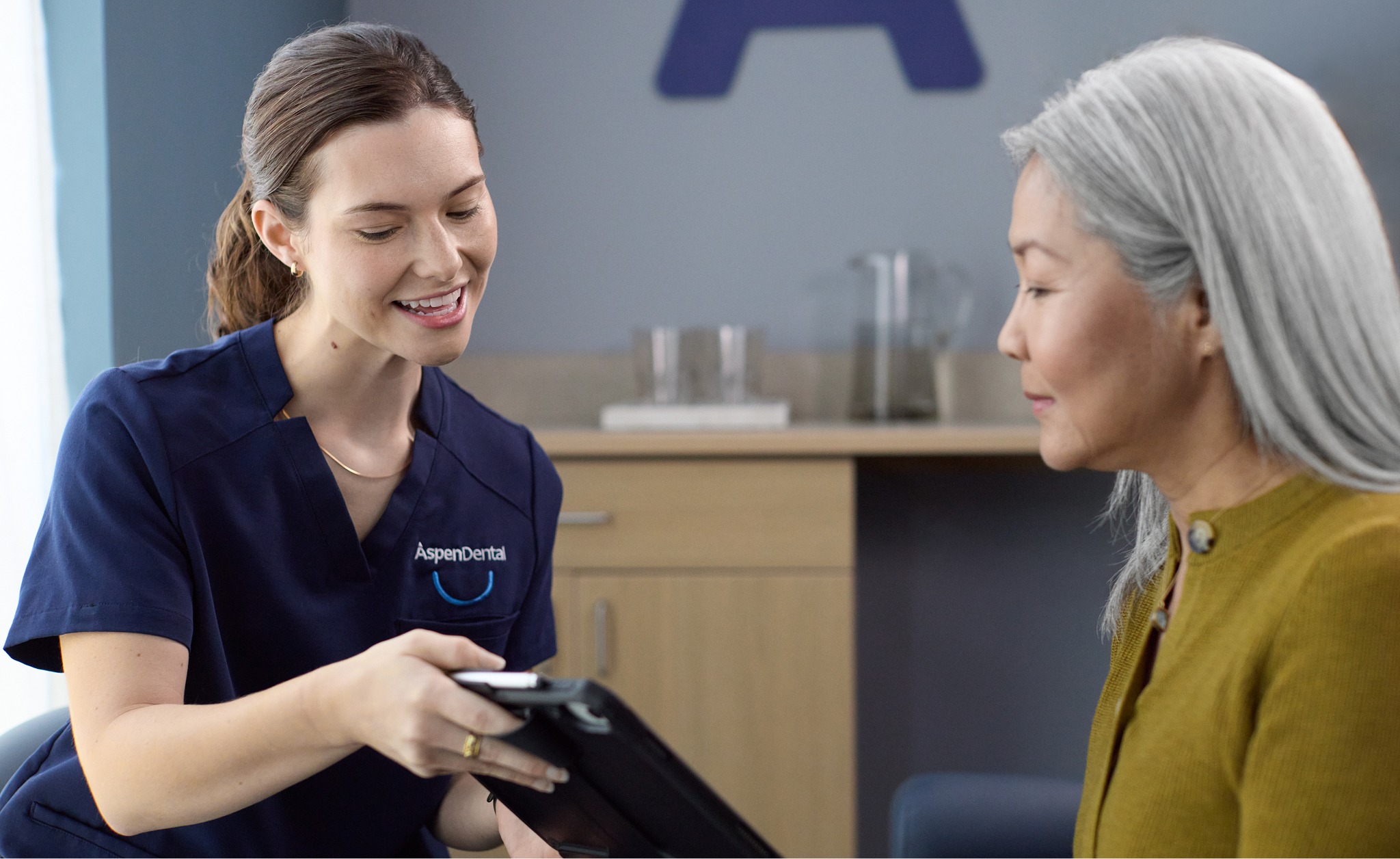 An Aspen Dental team member speaks with a patient during an in-office consultation about the cost of implant treatment.