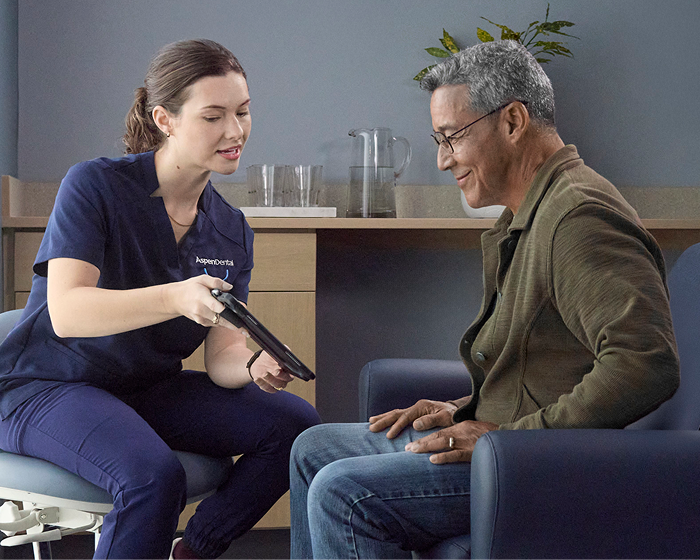 Aspen Dental team member reviewing information on a tablet with a patient.