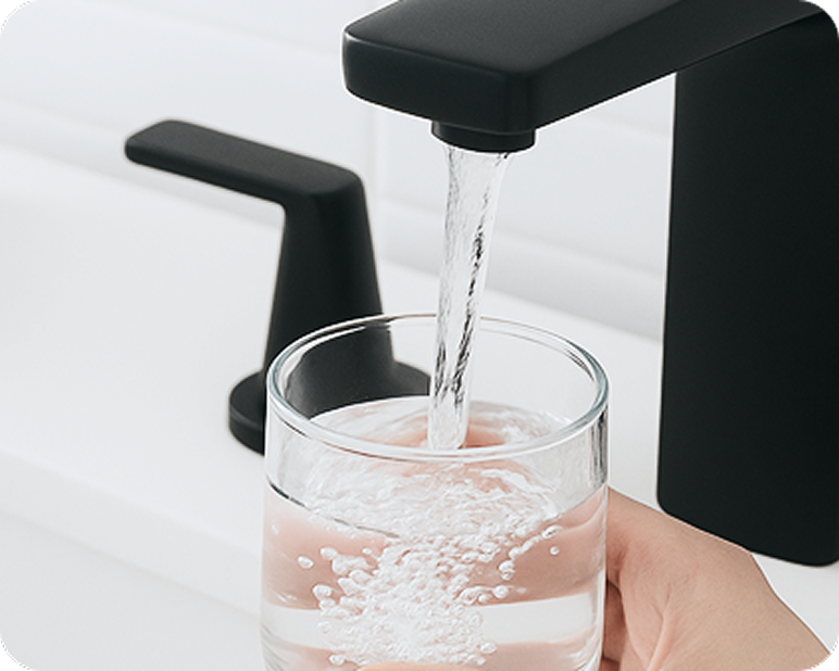 Water filling a glass from a faucet.