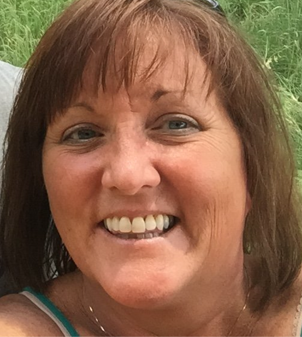 A smiling woman with brown hair and bangs