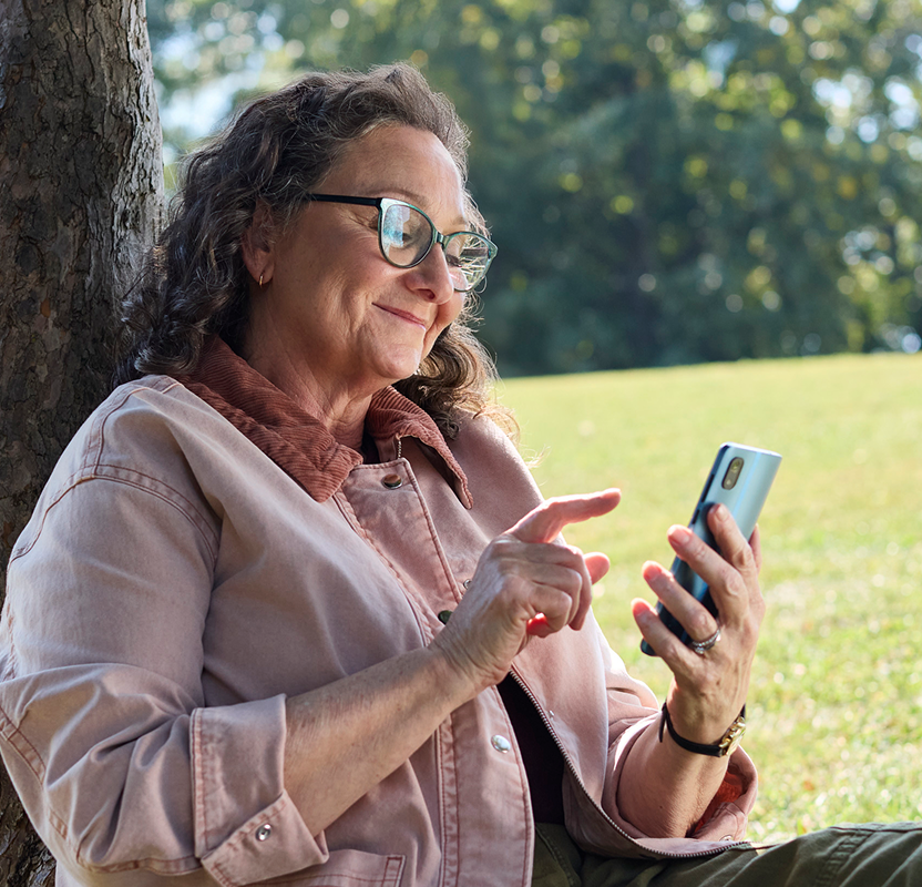 Woman smiling and looking at her smartphone outdoors.