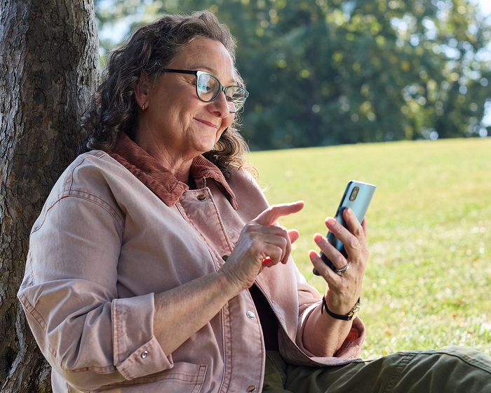 Woman smiling and looking at her smartphone outdoors.