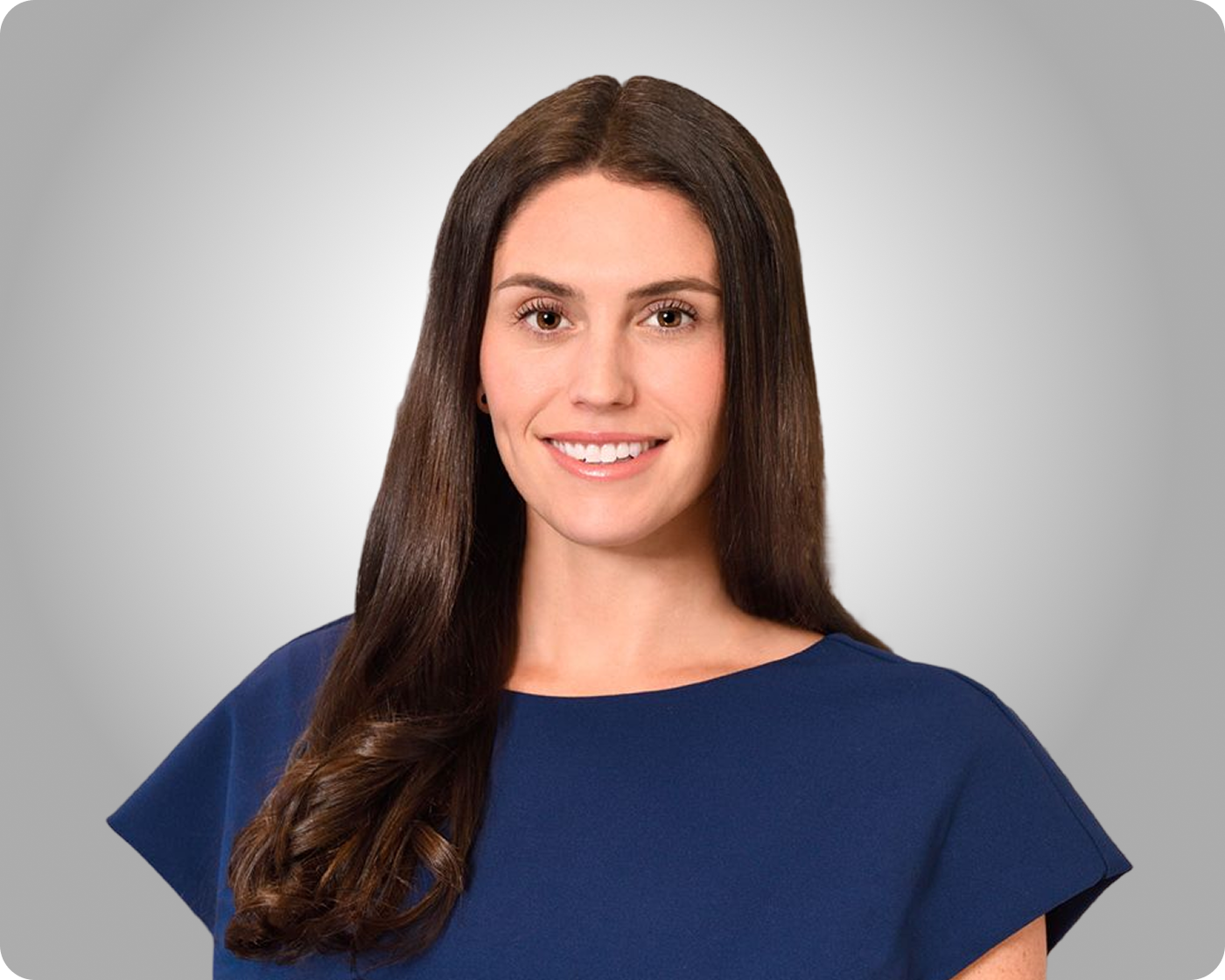 Professional headshot of a smiling woman with long dark hair wearing a navy blue top against a gray background