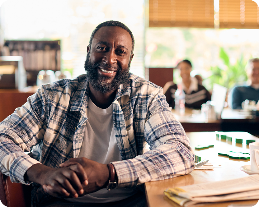 Alt text:
Smiling man seated at a table indoors.