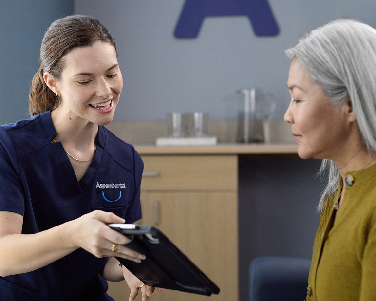 Alt text:
Aspen Dental team member reviewing information on a tablet with a patient during a visit.