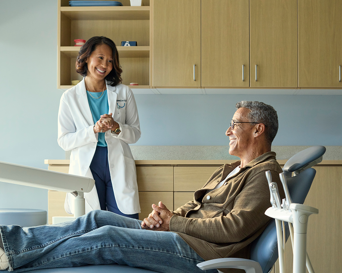 Female dentist speaking with a patient during a consultation in an exam room.