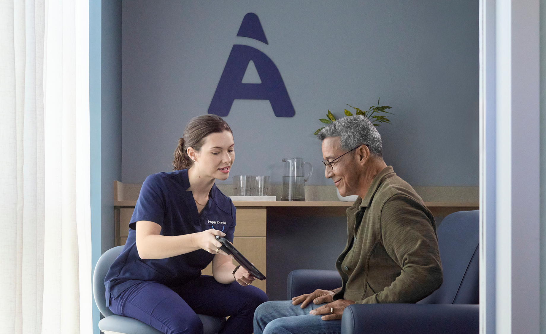 A healthcare professional reviews information on a tablet with a patient