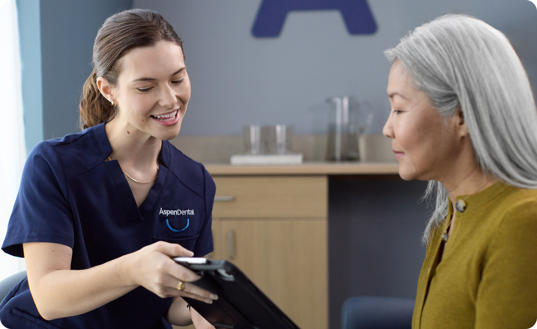 Dental professional from Aspen Dental reviewing treatment information with a senior patient during a consultation.