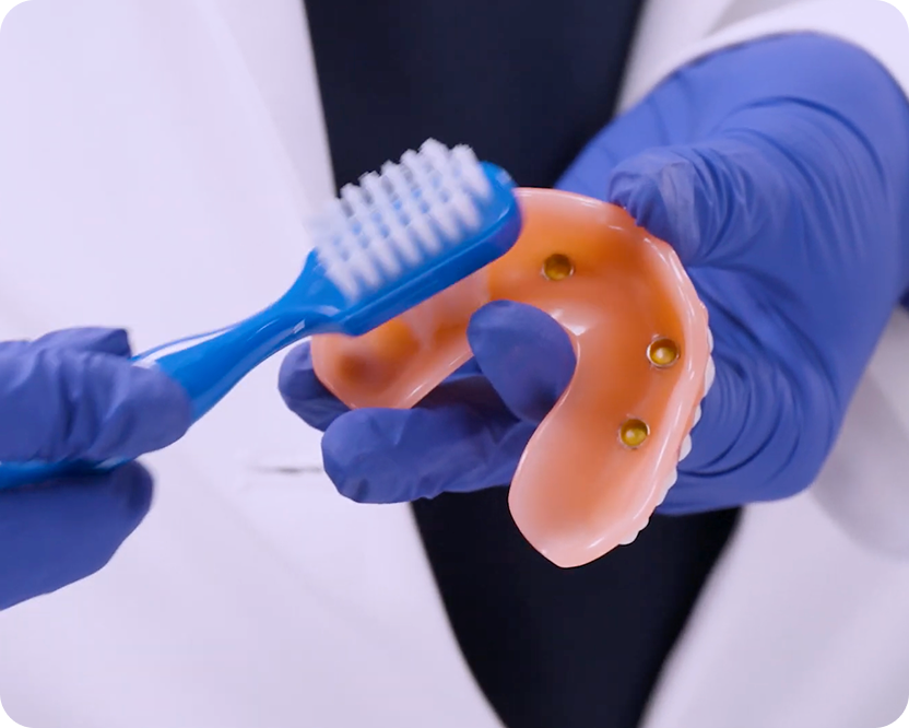 Alt text:
Dental professional brushing an implant-supported denture.