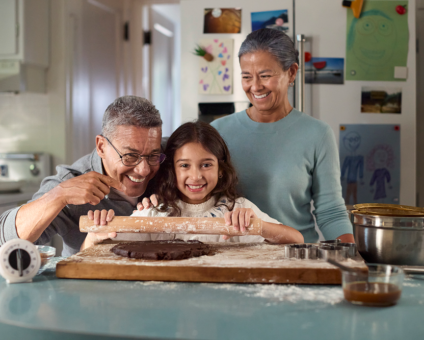 Alt text:
Grandparents and a young girl smiling while baking together in a kitchen.