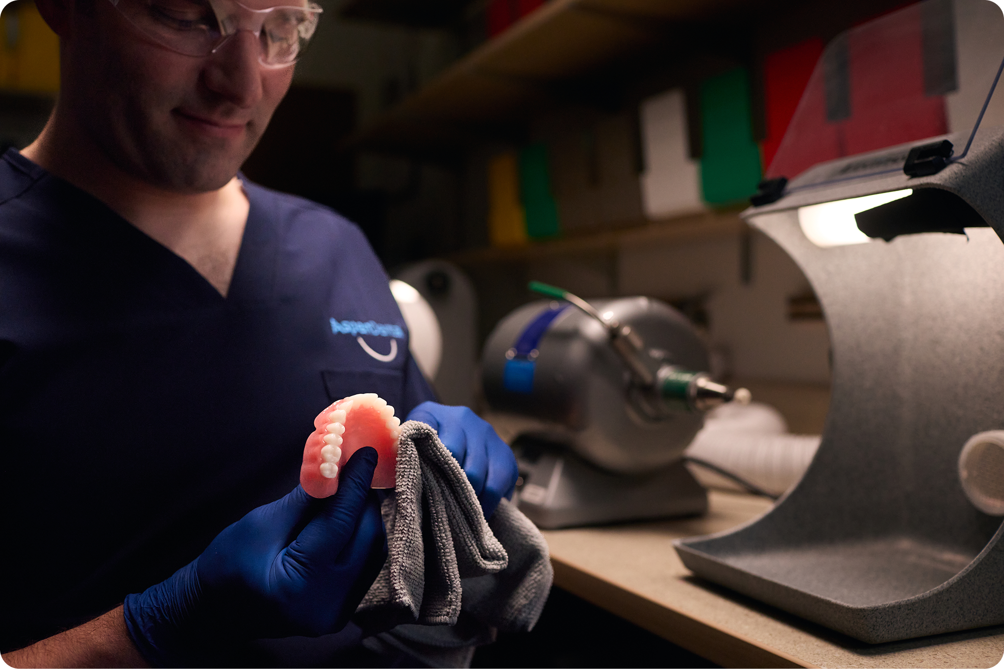 Dental professional repairing a denture in a lab setting.