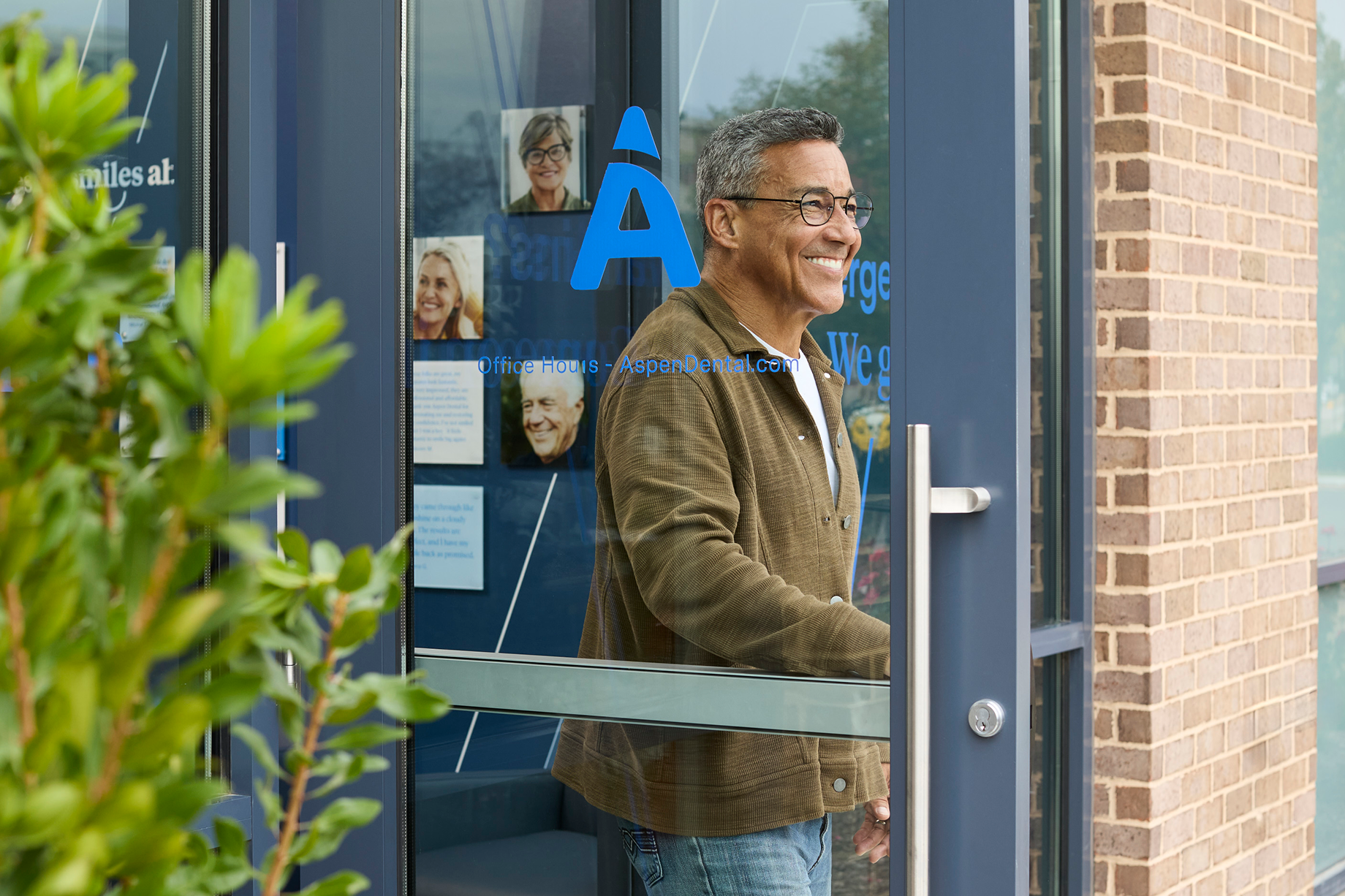 Alt text:
Smiling patient leaving an Aspen Dental office after a dental appointment.