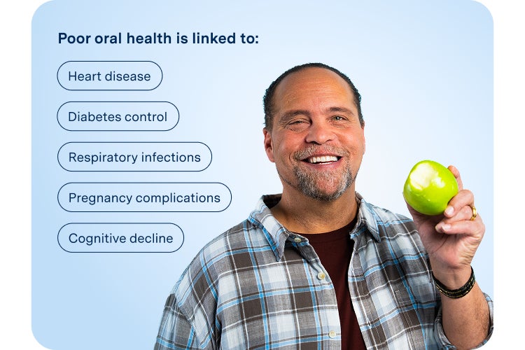A smiling man in a plaid shirt holds a green apple with a bite taken out of it, symbolizing confidence and comfort after dental treatment, against a light blue background.
