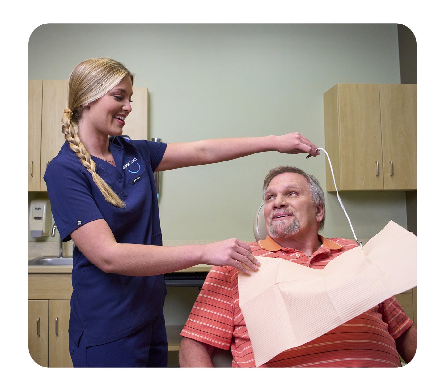Dental assistant placing a bib on a patient