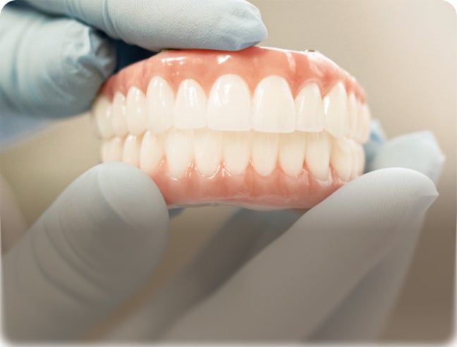 Full mouth dental implants held in gloved hands with overlay text: “Full mouth implants. Clear pricing. No surprises.”