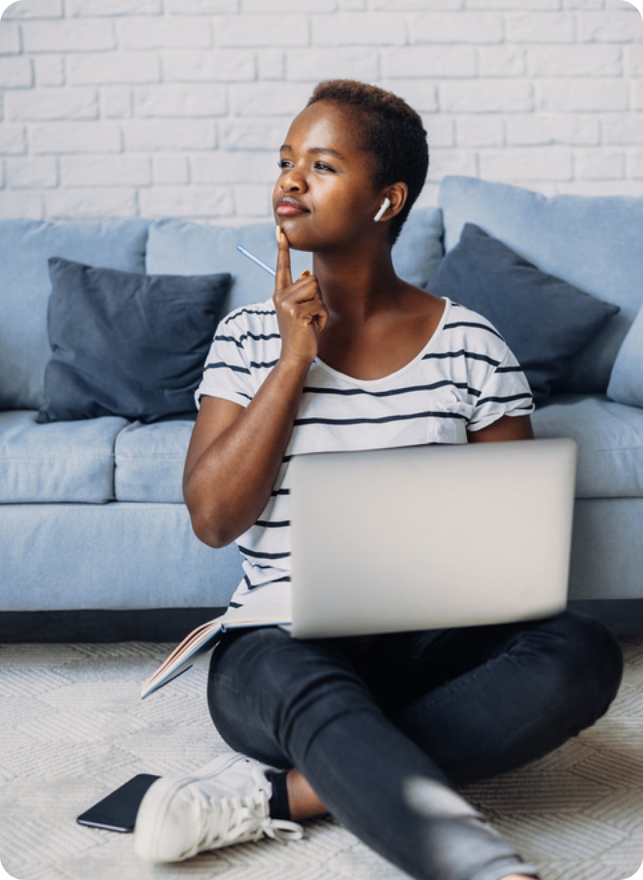 Woman sitting with a laptop and touching her chin, suggesting concern about thick or stringy saliva after tooth pain.