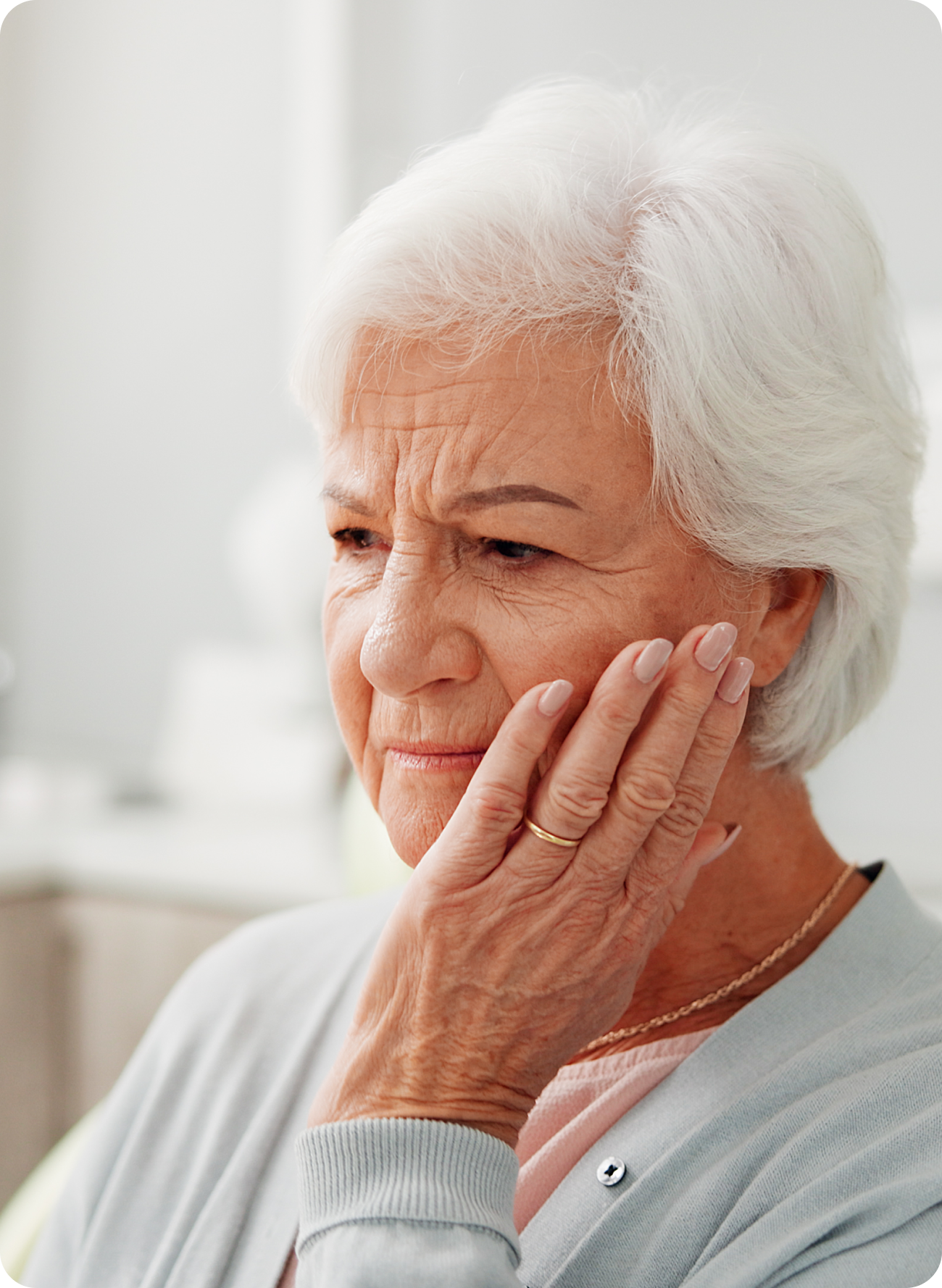 An older woman holding her jaw with a pained expression