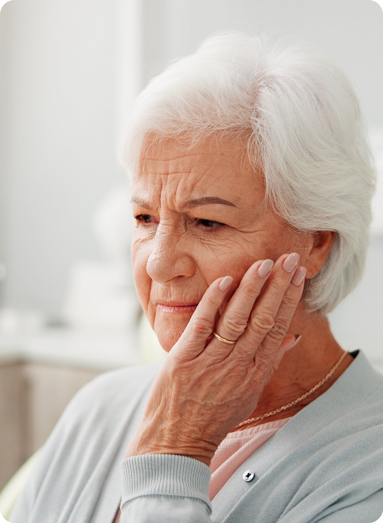 An older woman holding her jaw with a pained expression