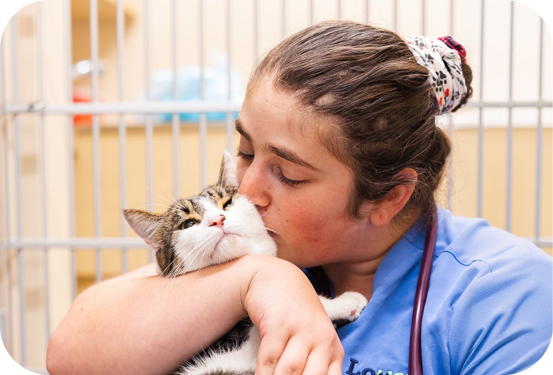 A caregiver shares a cheek kiss with a cat