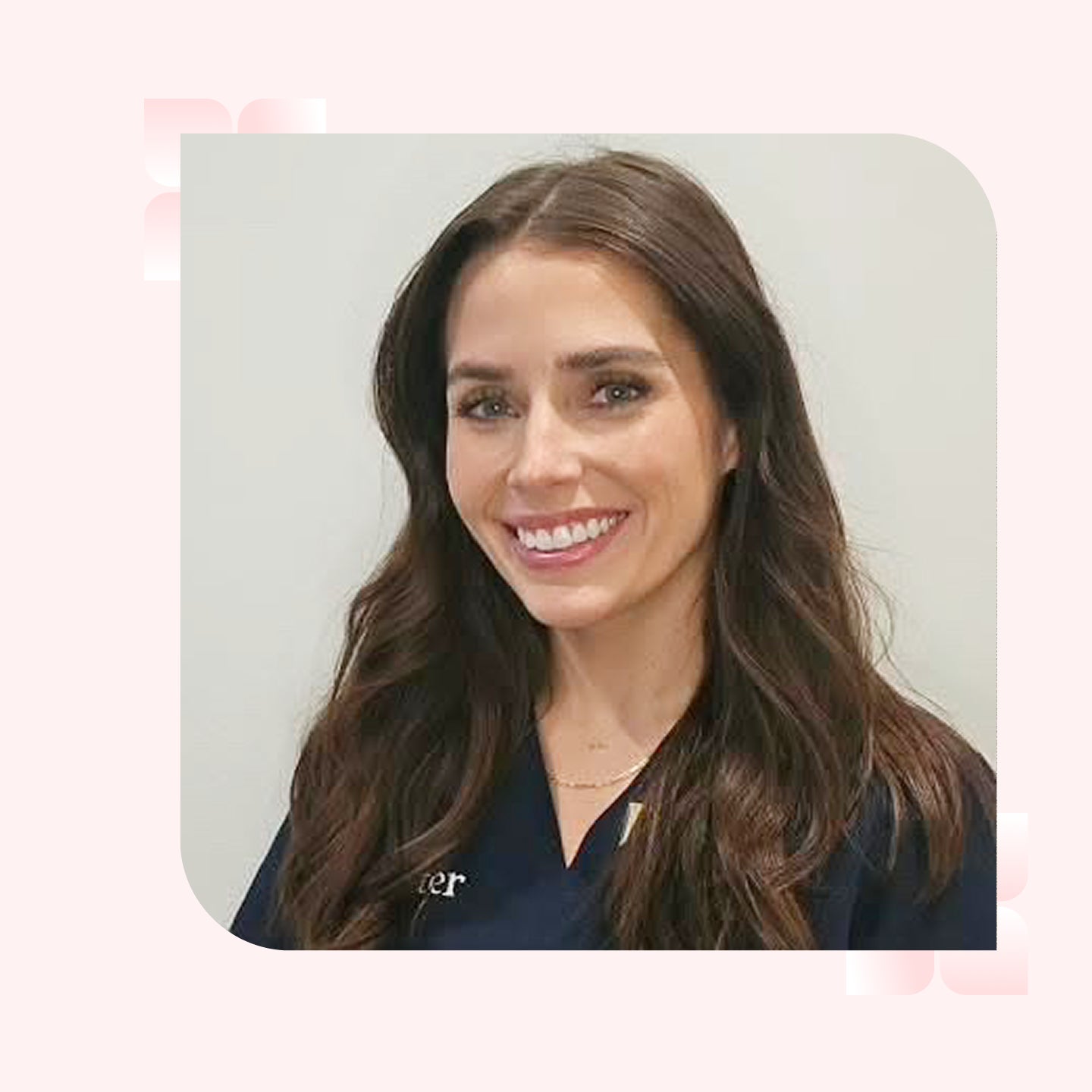 A headshot of a smiling woman with long wavy brunette hair