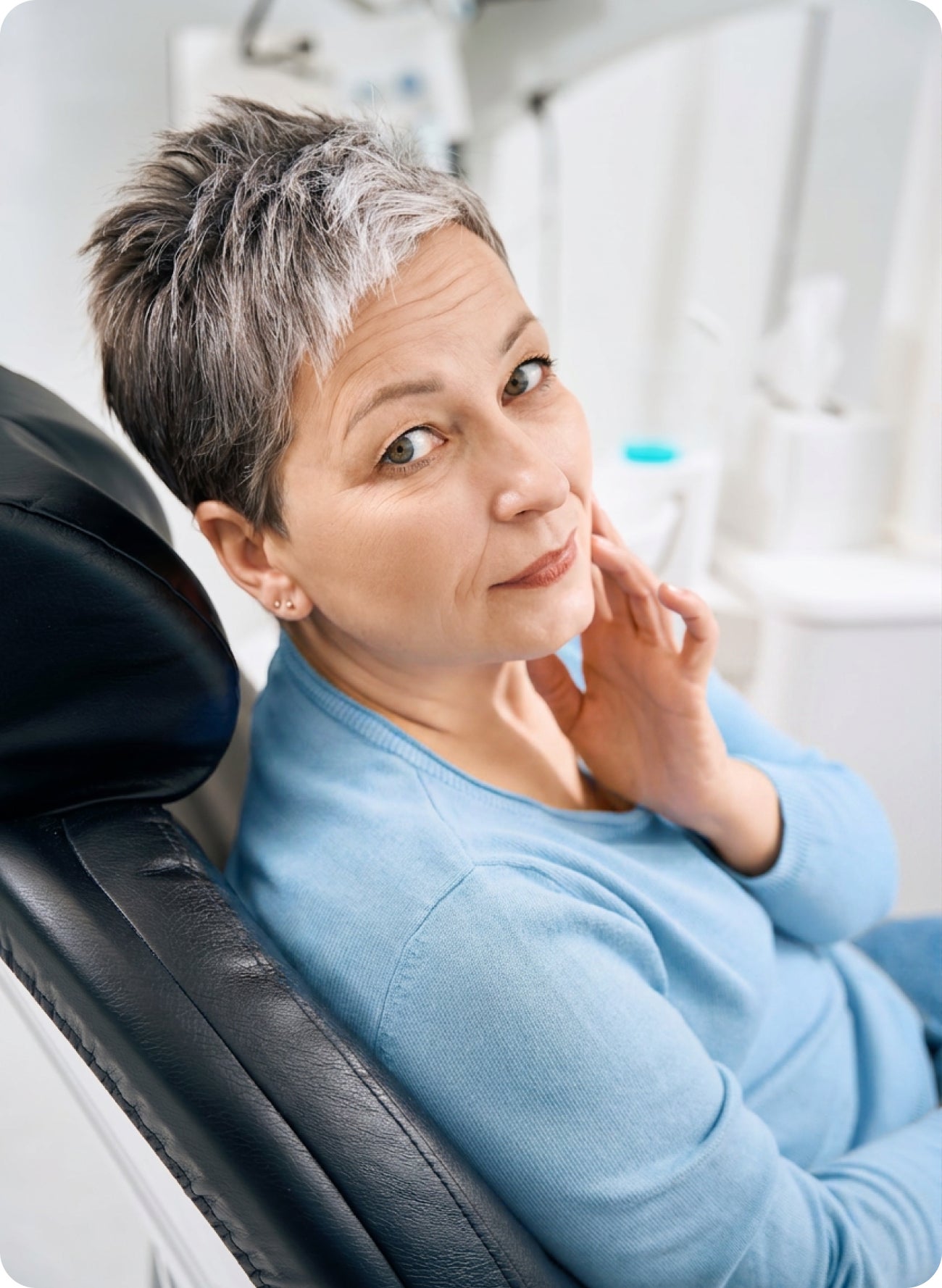 Woman sitting in a dental chair with a thoughtful expression, suggesting questions about needing a root canal even when a tooth does not hurt.