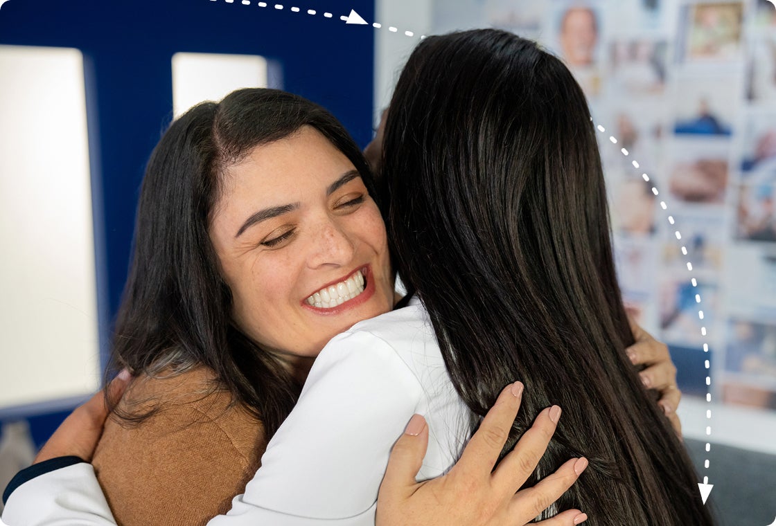A patient smiling warmly as she hugs her ClearChoice dental provider, celebrating her new smile and treatment experience.