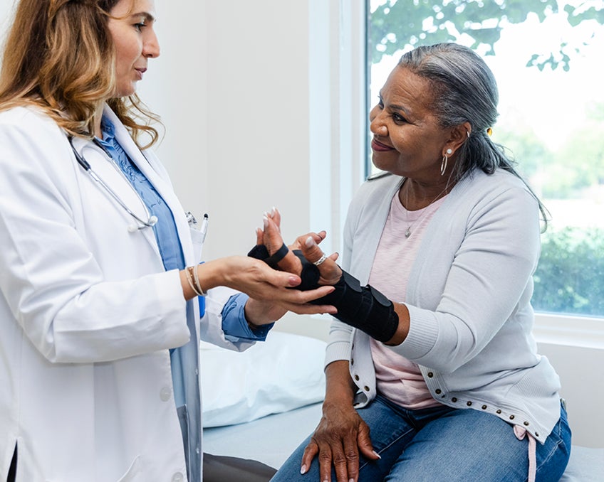 A provider meets with a patient wearing a wrist brace.