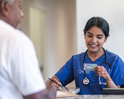 A WellNow team member taking a patient's insurance card information.