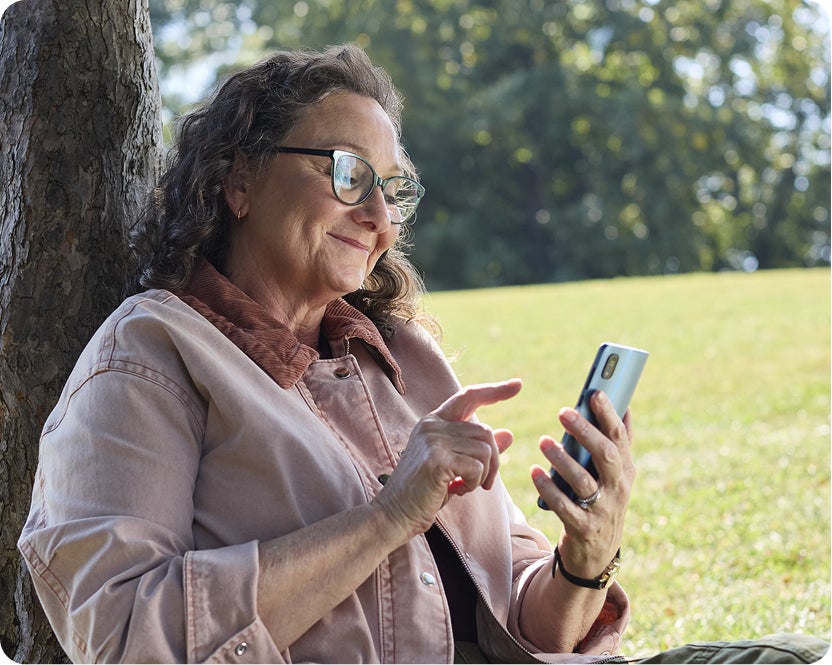 Smiling woman uses smartphone outdoors