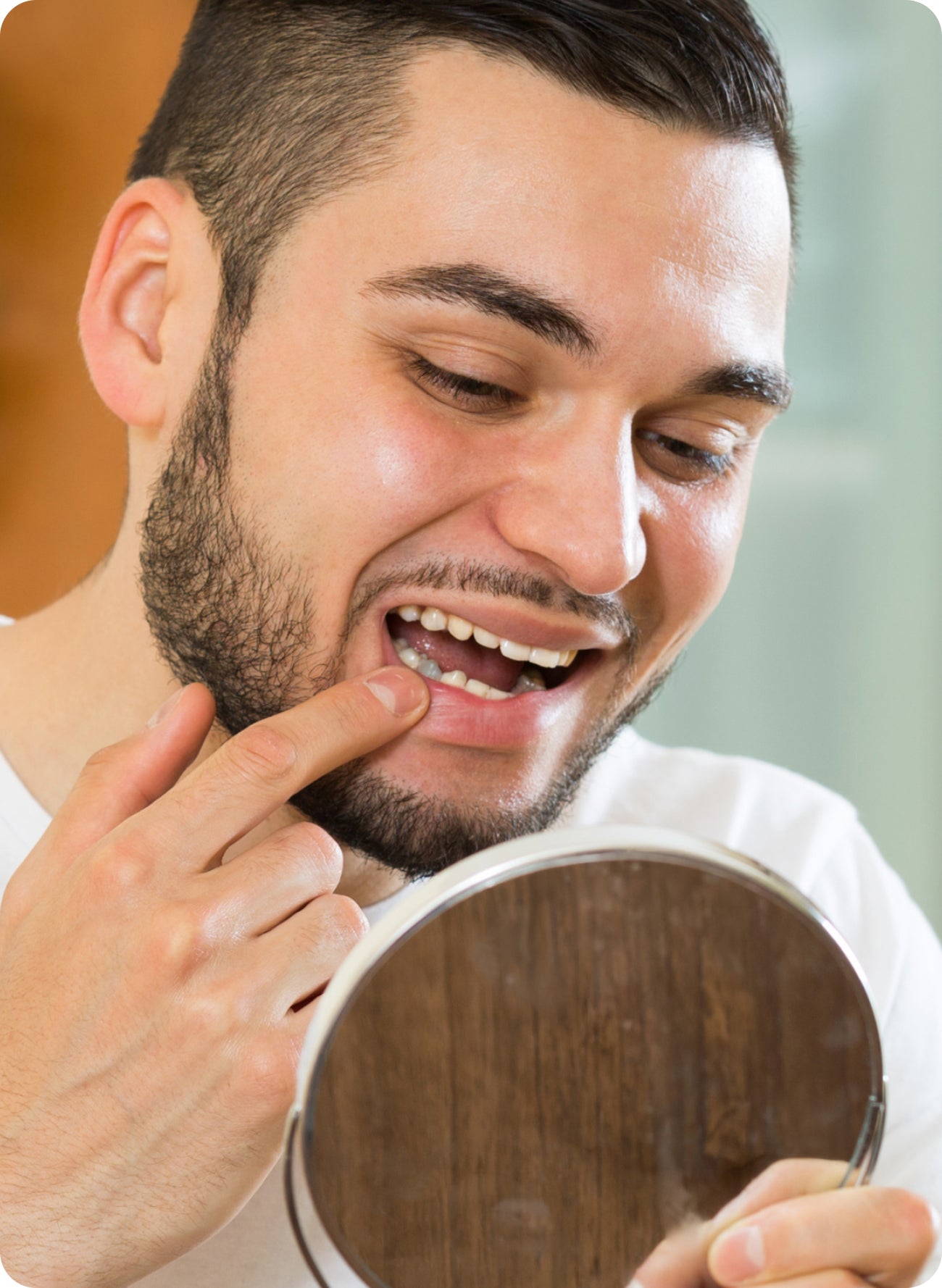 Man looking in a mirror and pointing at his tooth, suggesting concern about a tooth turning grey.