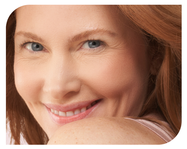 A smiling redhead with blue eyes looks over her shoulder