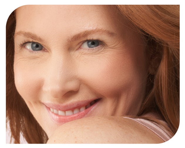 A smiling redhead with blue eyes looks over her shoulder