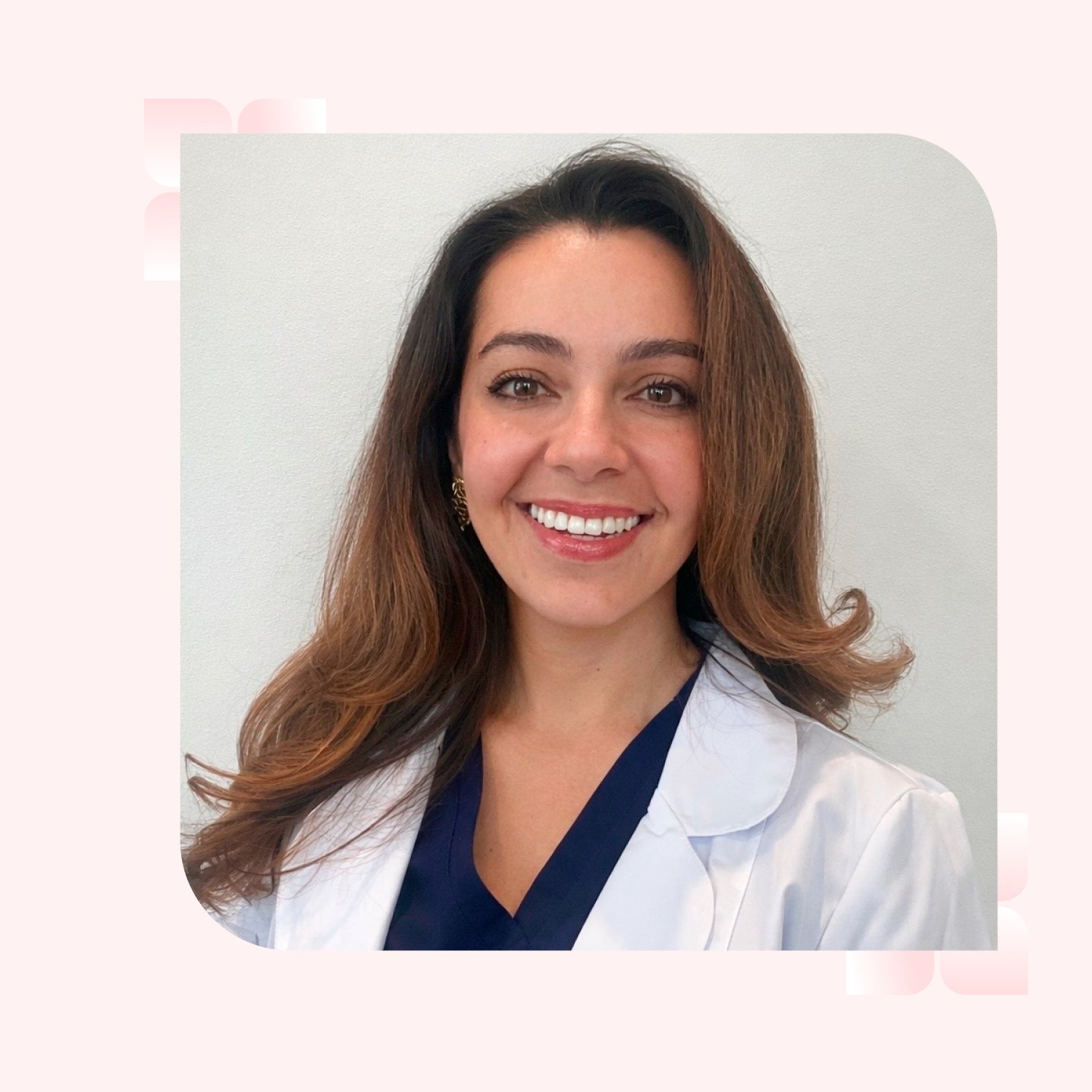 A headshot of a smiling brunette woman wearing a white lab coat