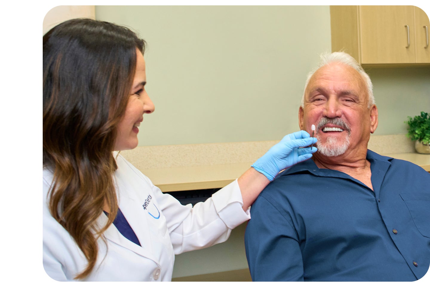 A smiling dental professional consulting with an older male patient during a veneers appointment, highlighting improving the look of your smile and personalized care.