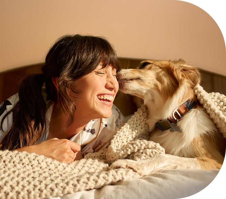 Pet parent cuddling her dog and smiling.