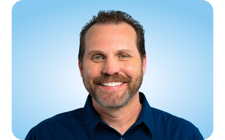 Portrait of a person wearing a dark blue collared shirt, standing against a light blue background.